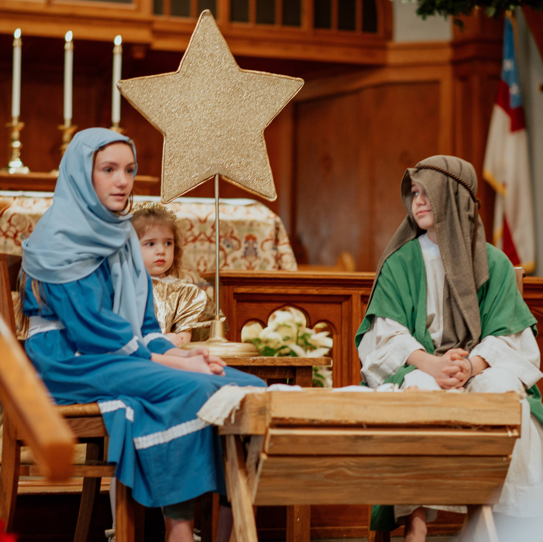 A woman in a blue dress is sitting next to a boy in a green robe