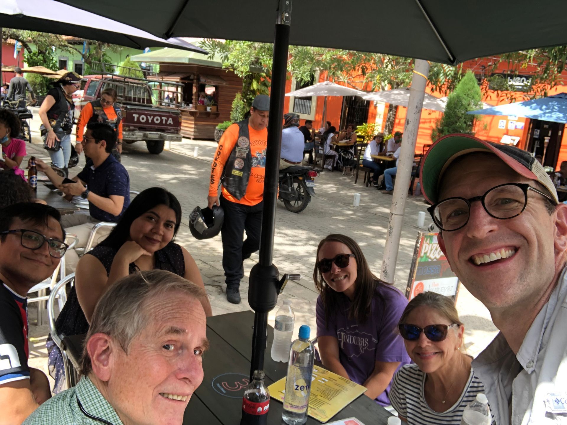 A group of people are sitting at a table under an umbrella.