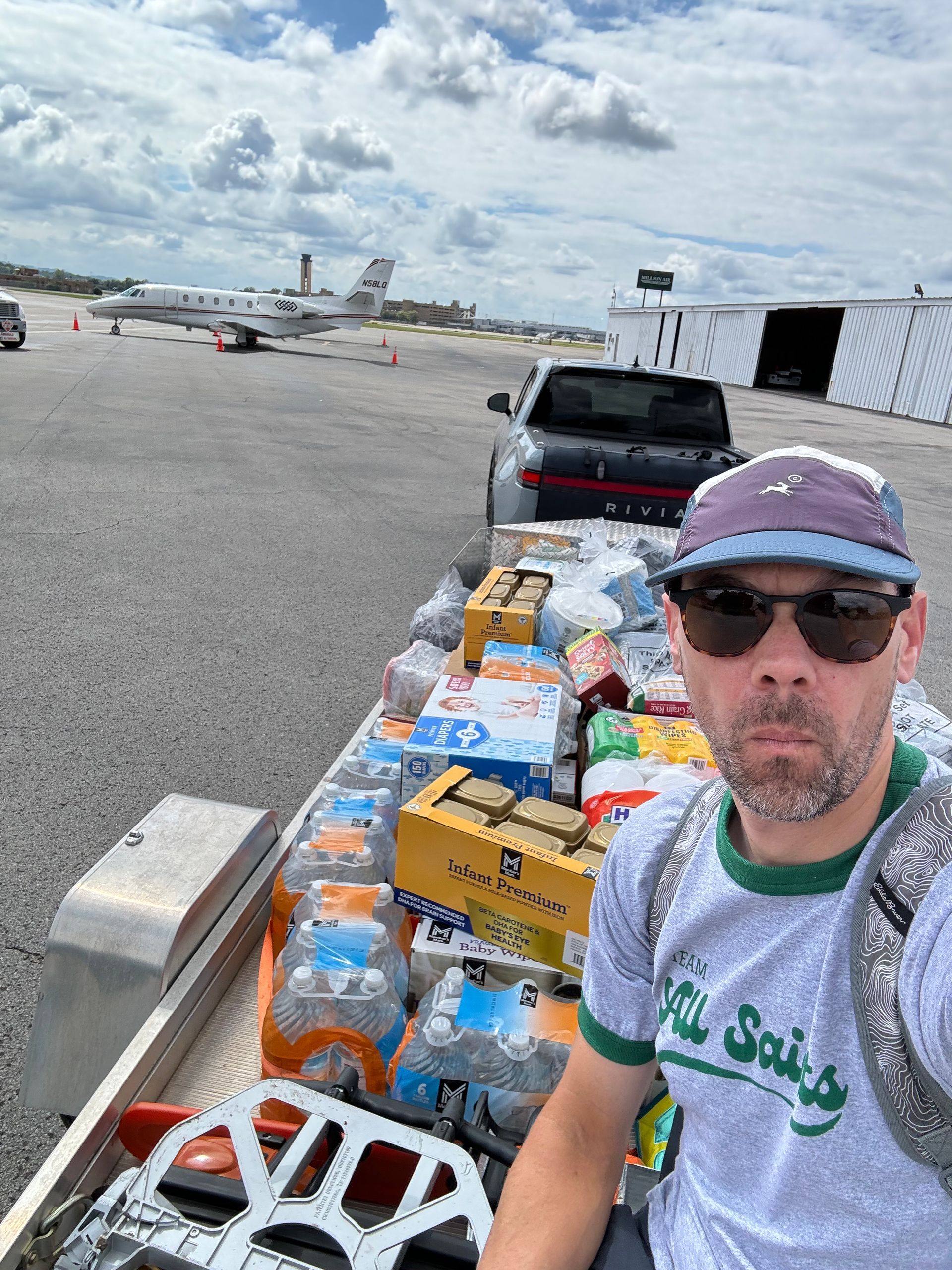 A man is sitting on a trailer filled with bottles of water.
