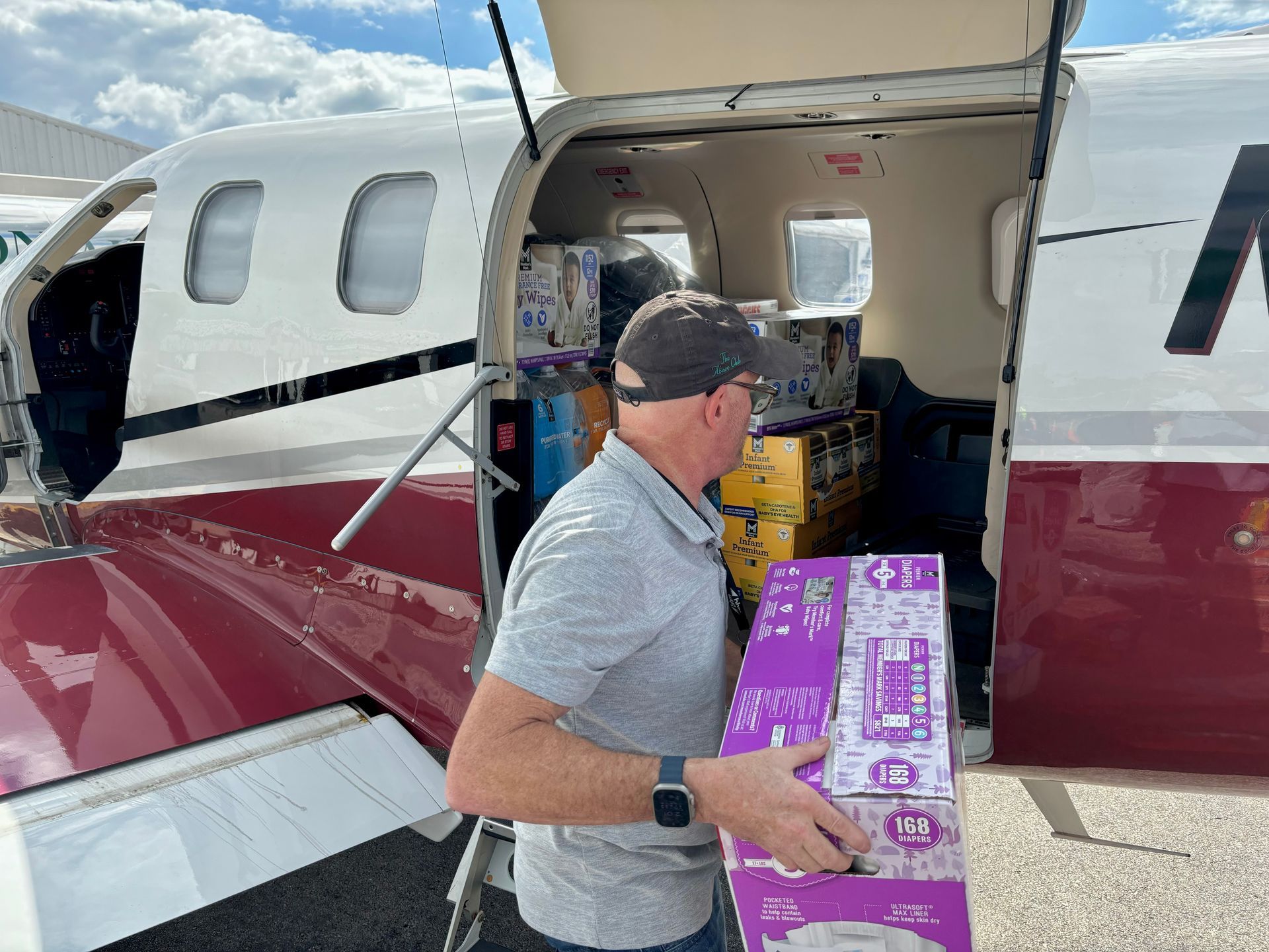 A man is loading a purple box into an airplane.