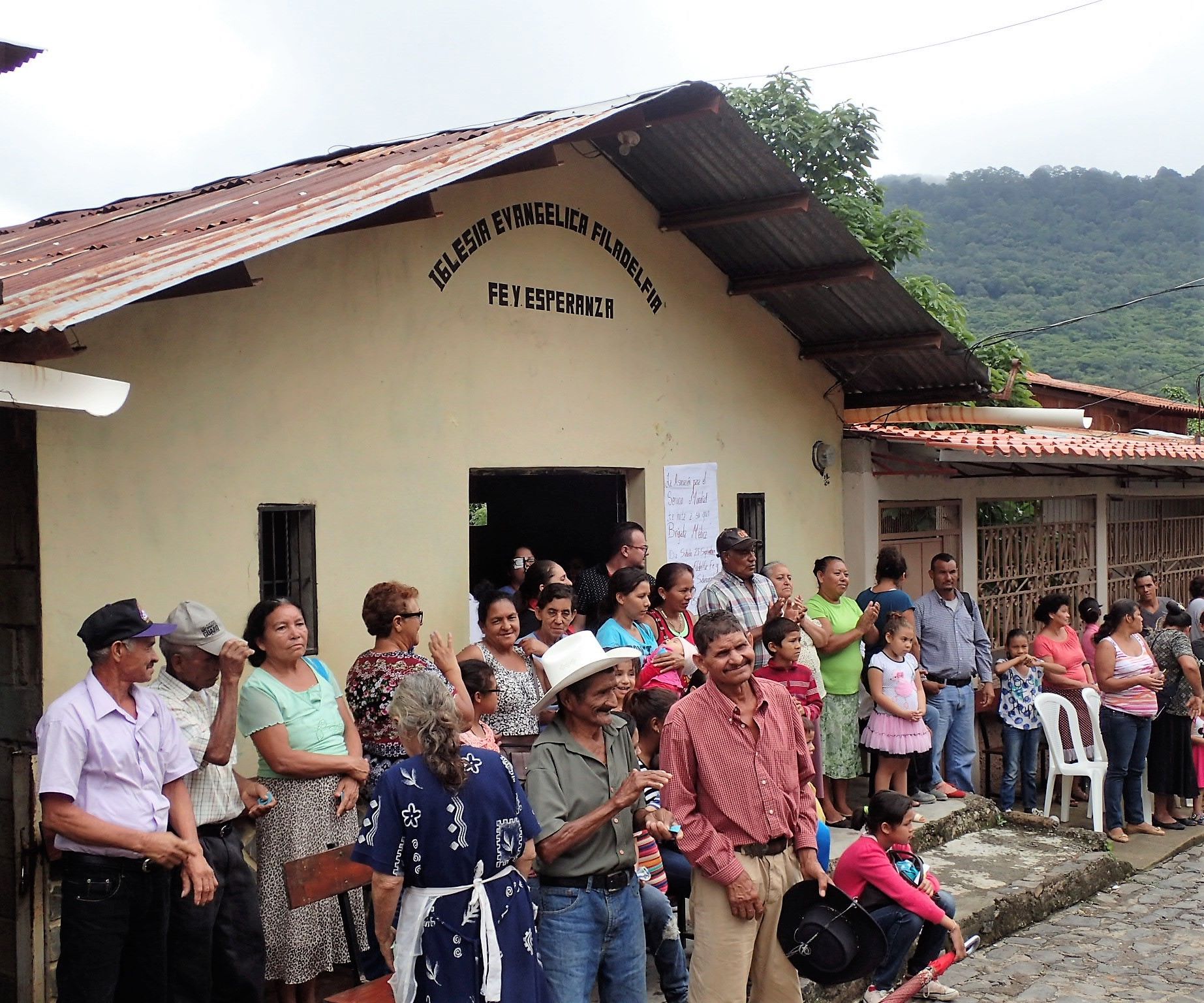 A group of people standing in front of a building that says rey esperanza
