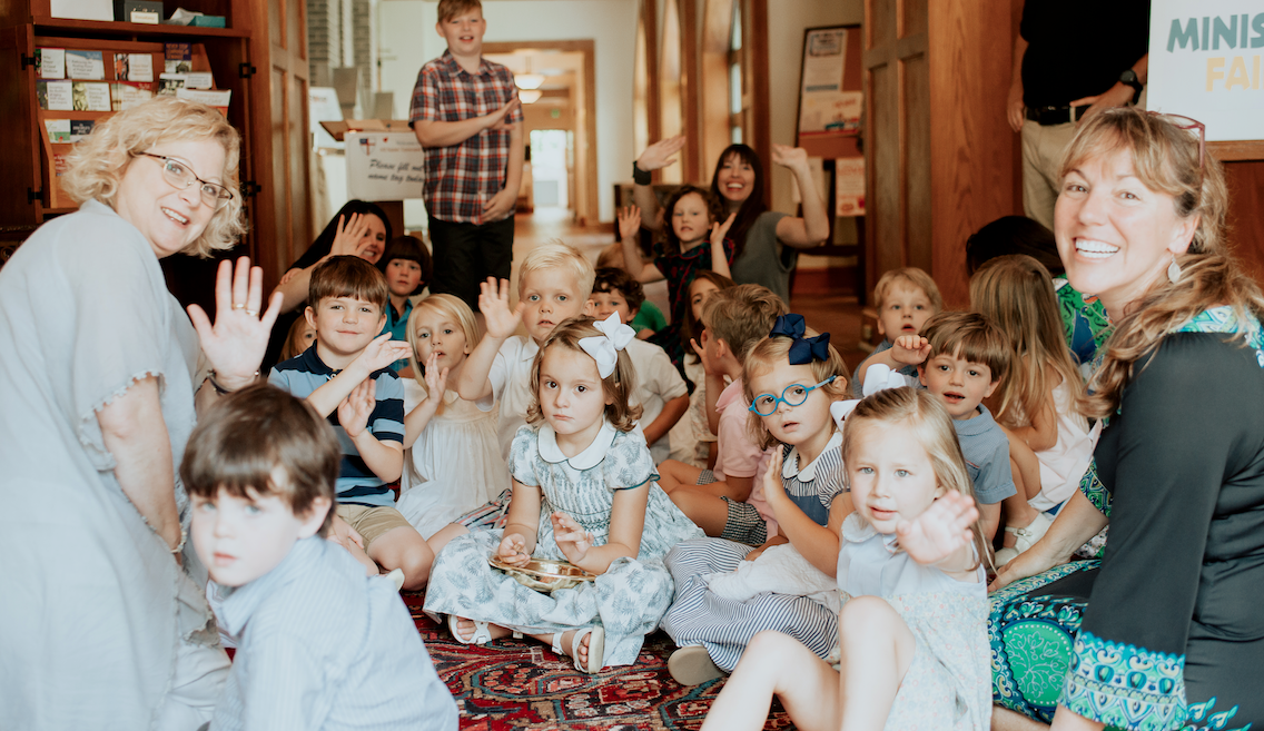 A group of children are sitting on the floor in a room.