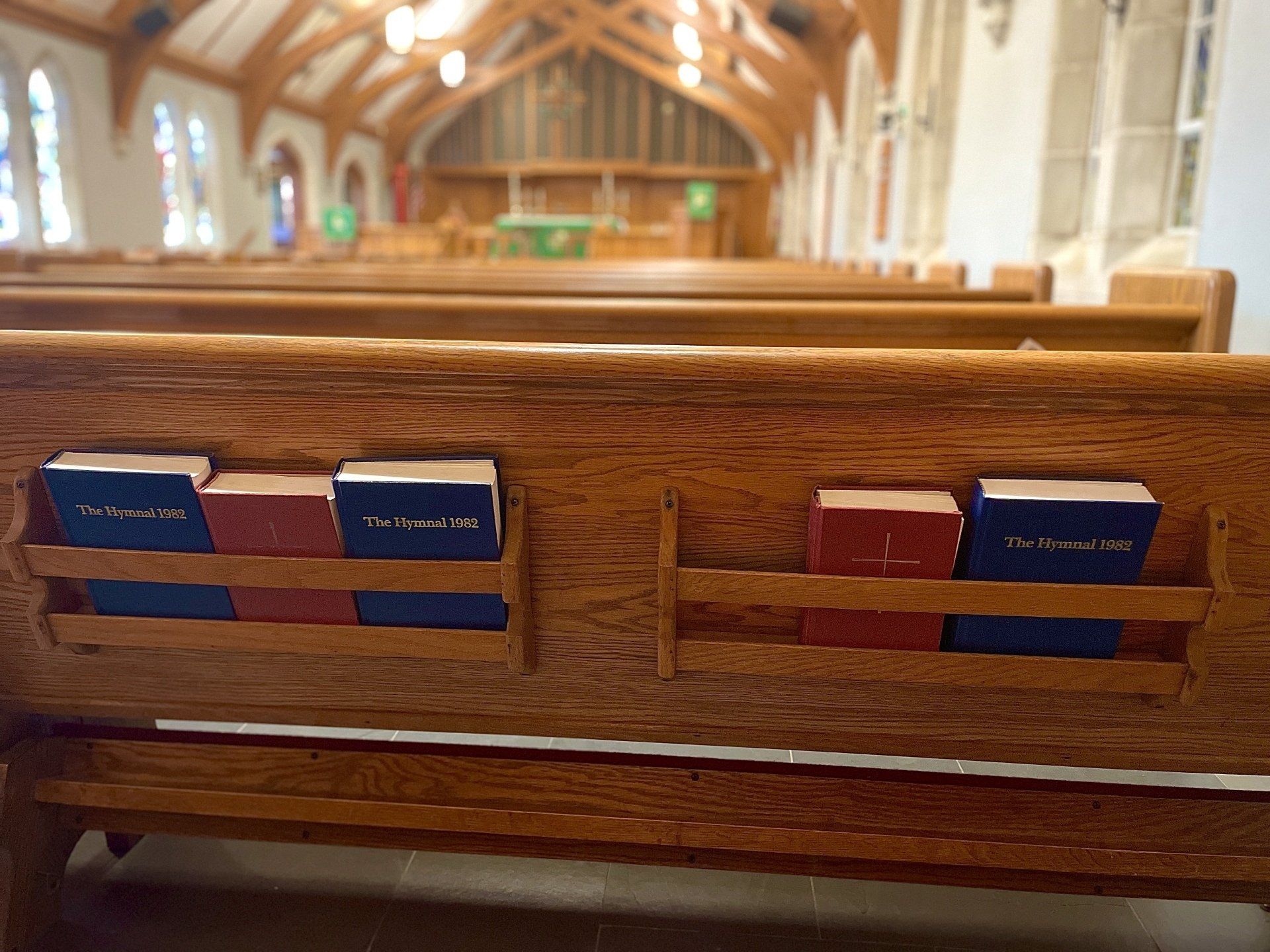A row of wooden benches in a church with books on them.