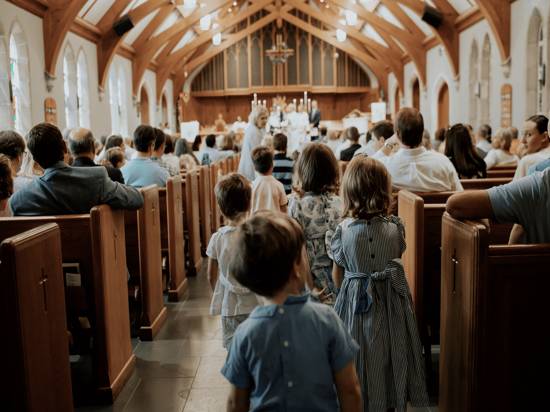 A group of children are walking down the aisle of a church.