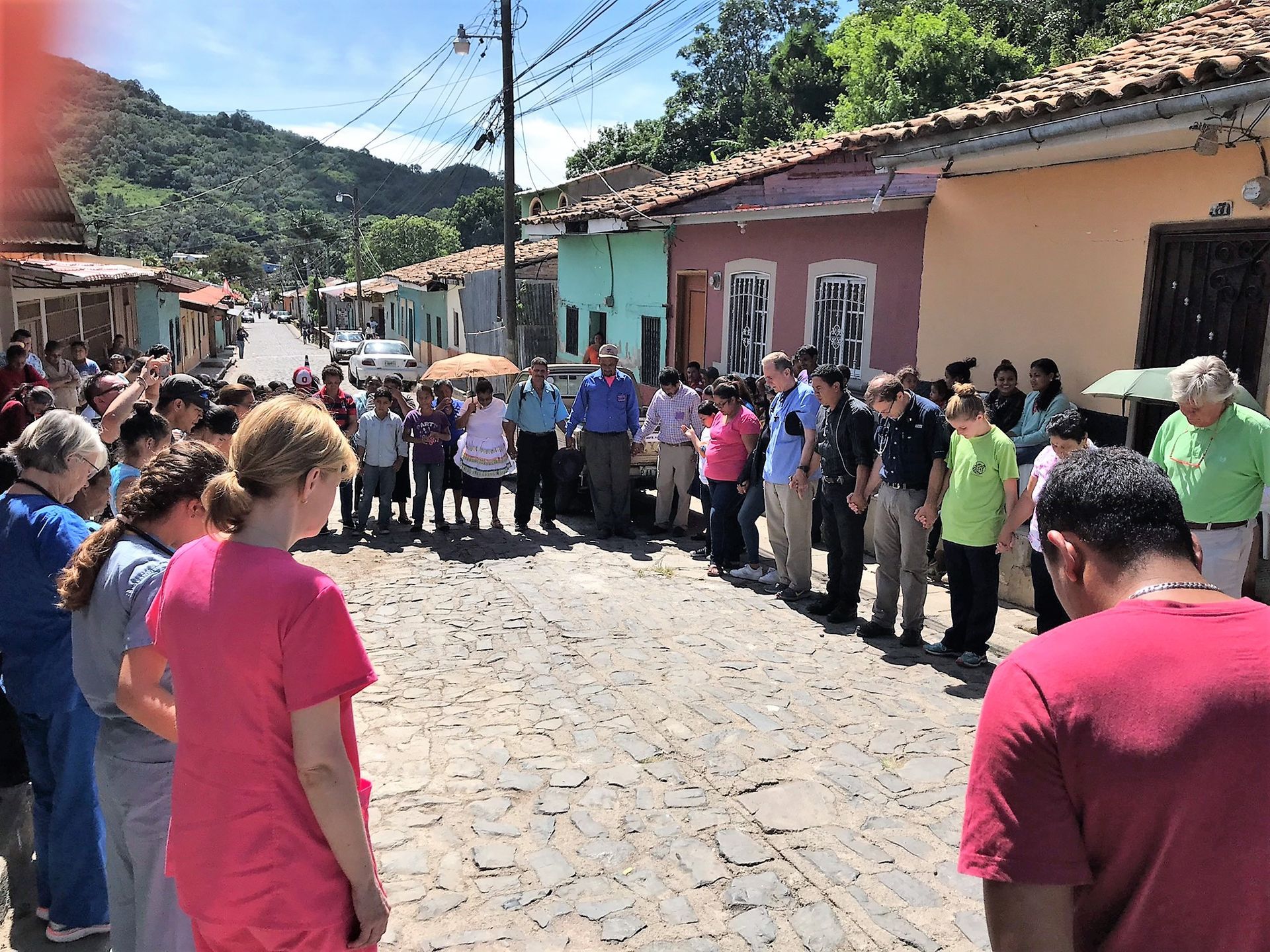 A group of people are standing on a cobblestone street.