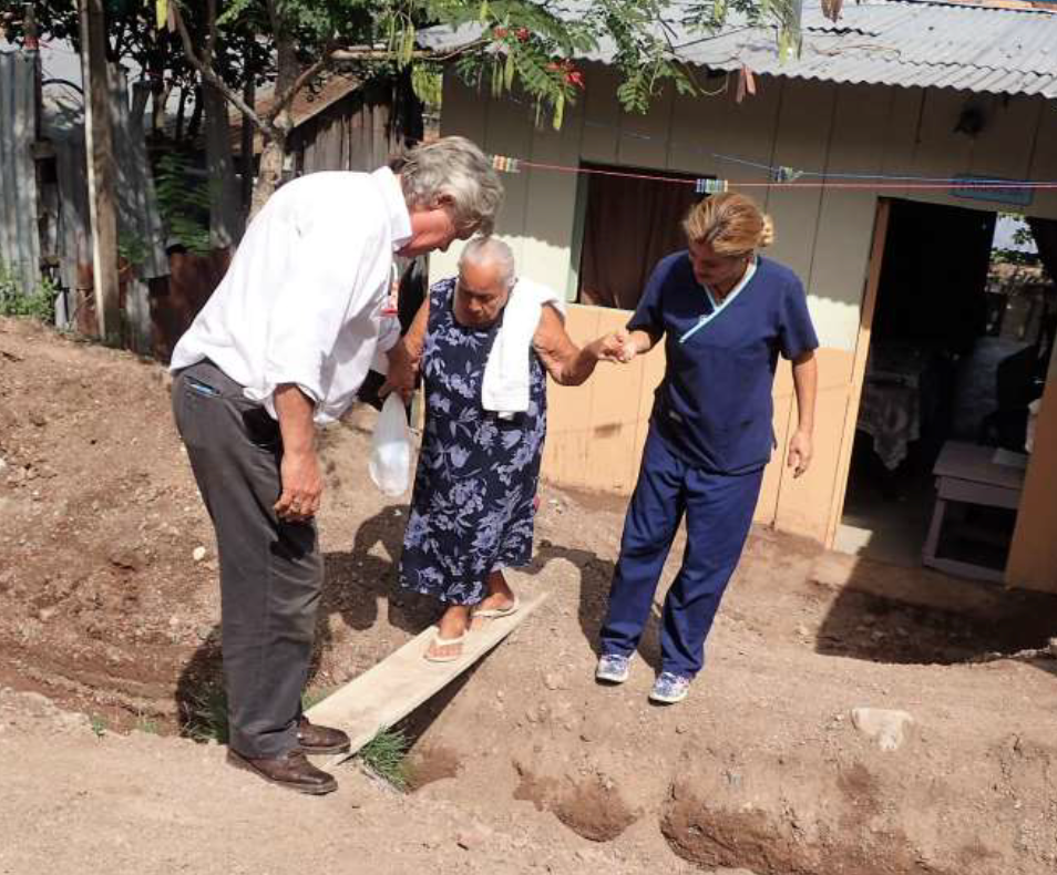 A man helps an elderly woman walk on a board