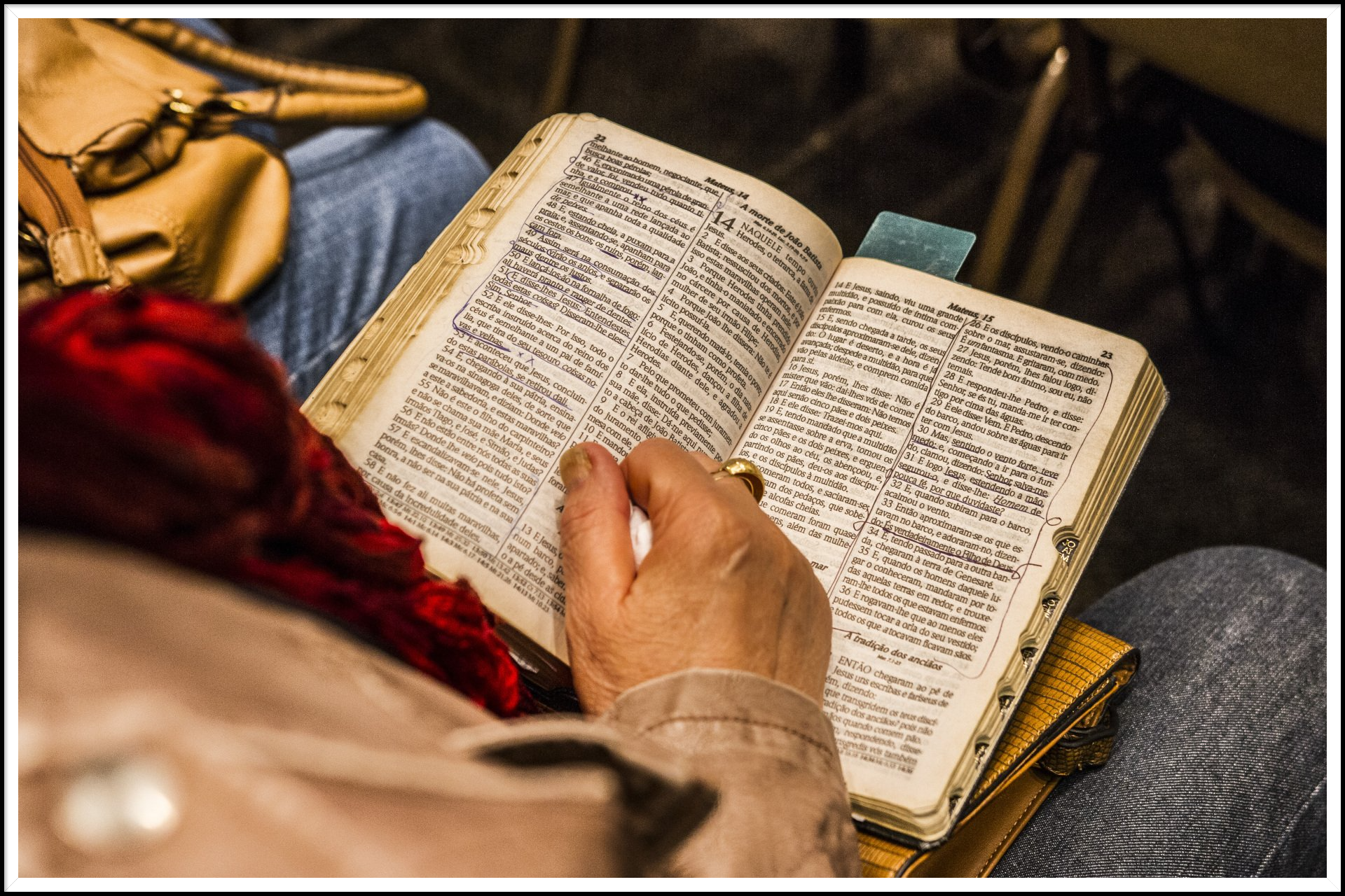 A person is reading a bible while sitting in a chair.