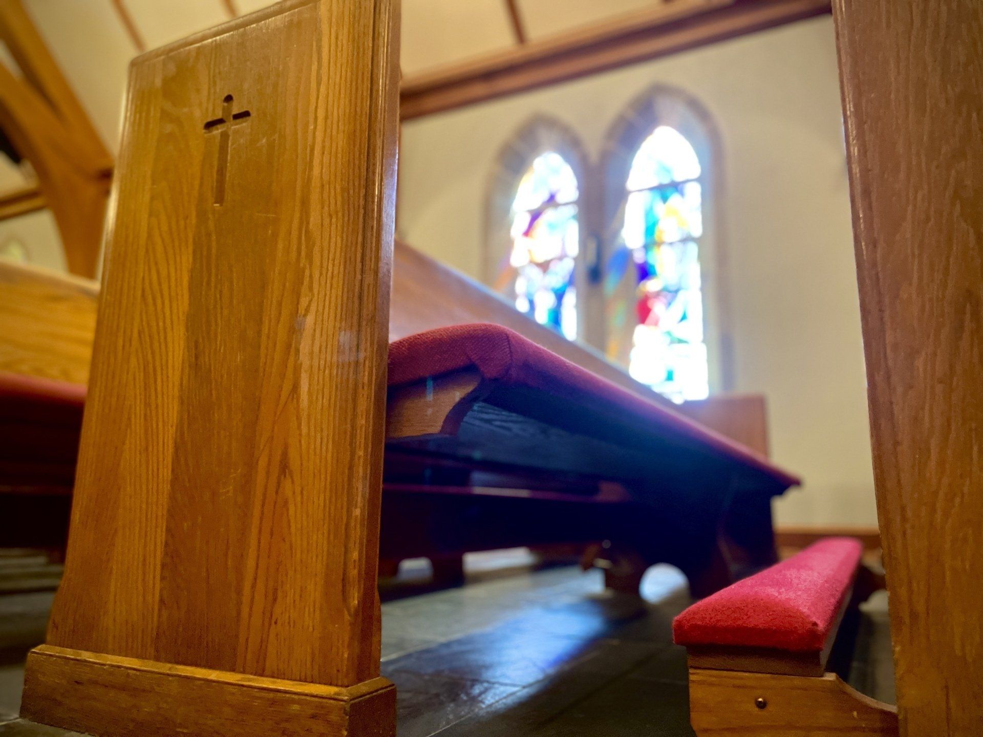 A church with a stained glass window and wooden benches