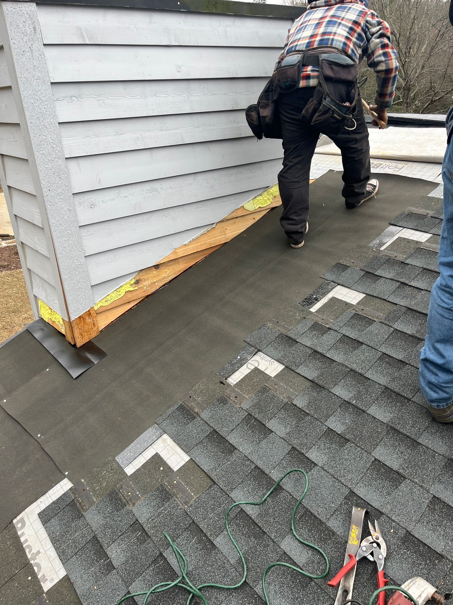 A man is working on a roof with a pair of pliers.