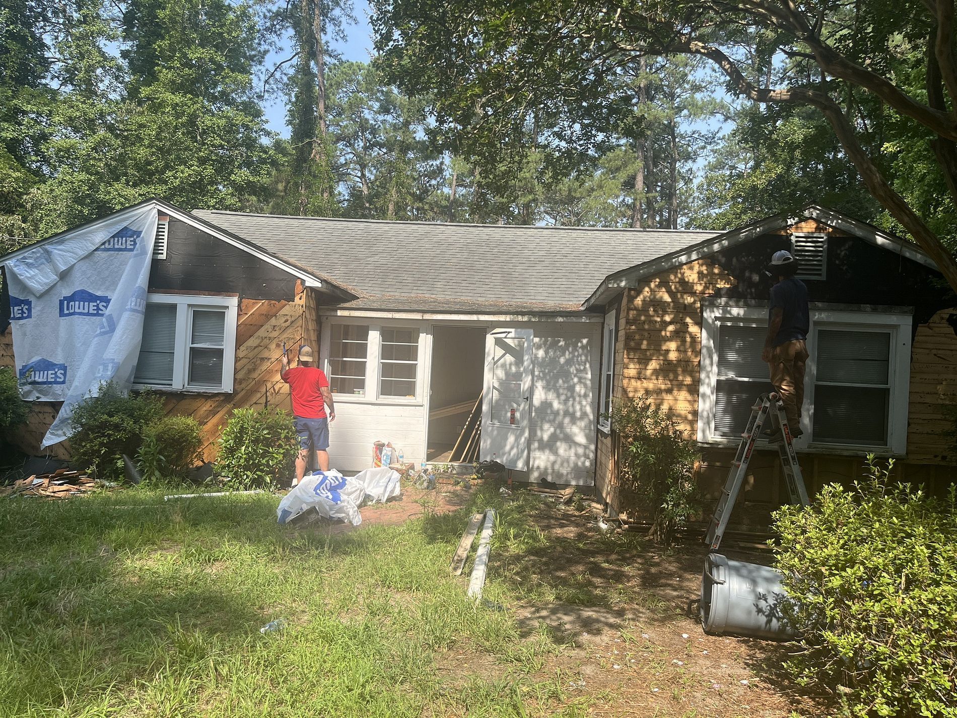 A man is standing in front of a house that is being remodeled.