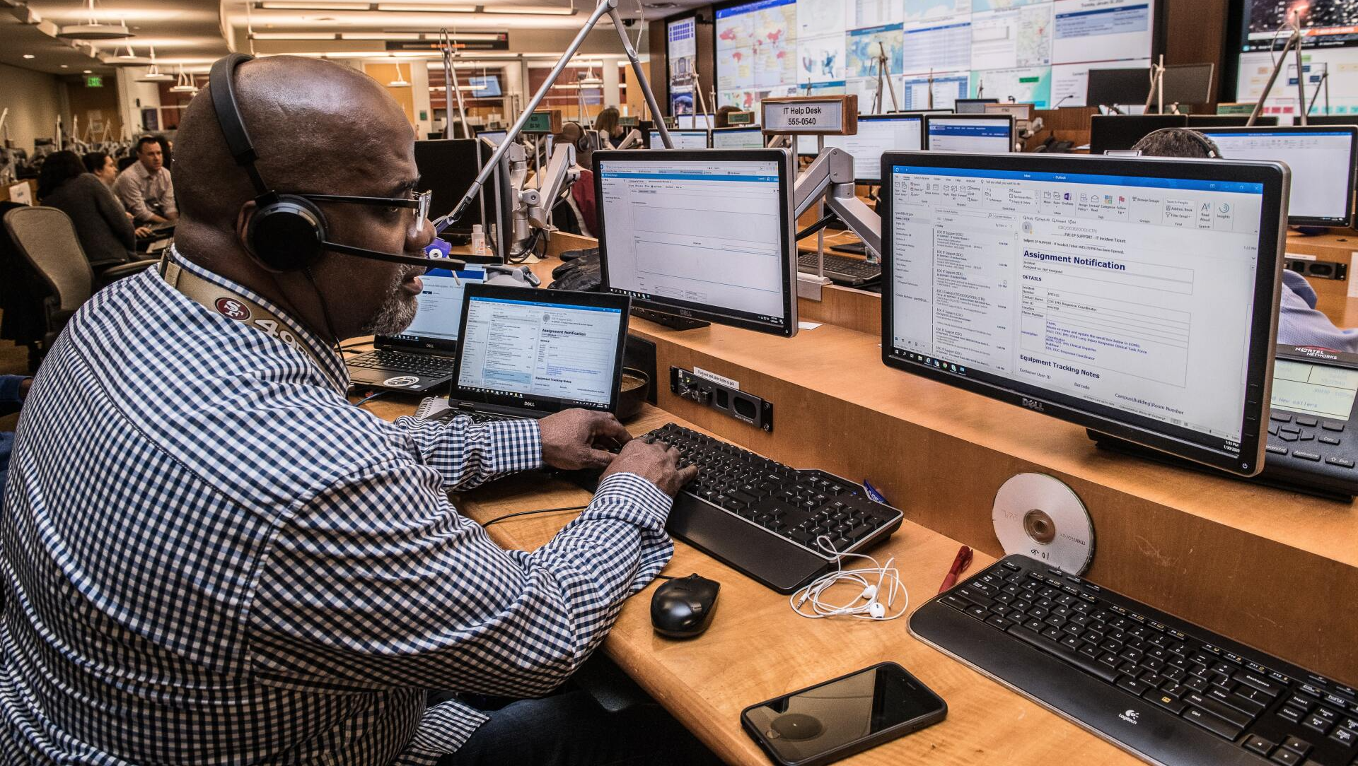 A man wearing headphones is sitting at a desk in front of a computer.