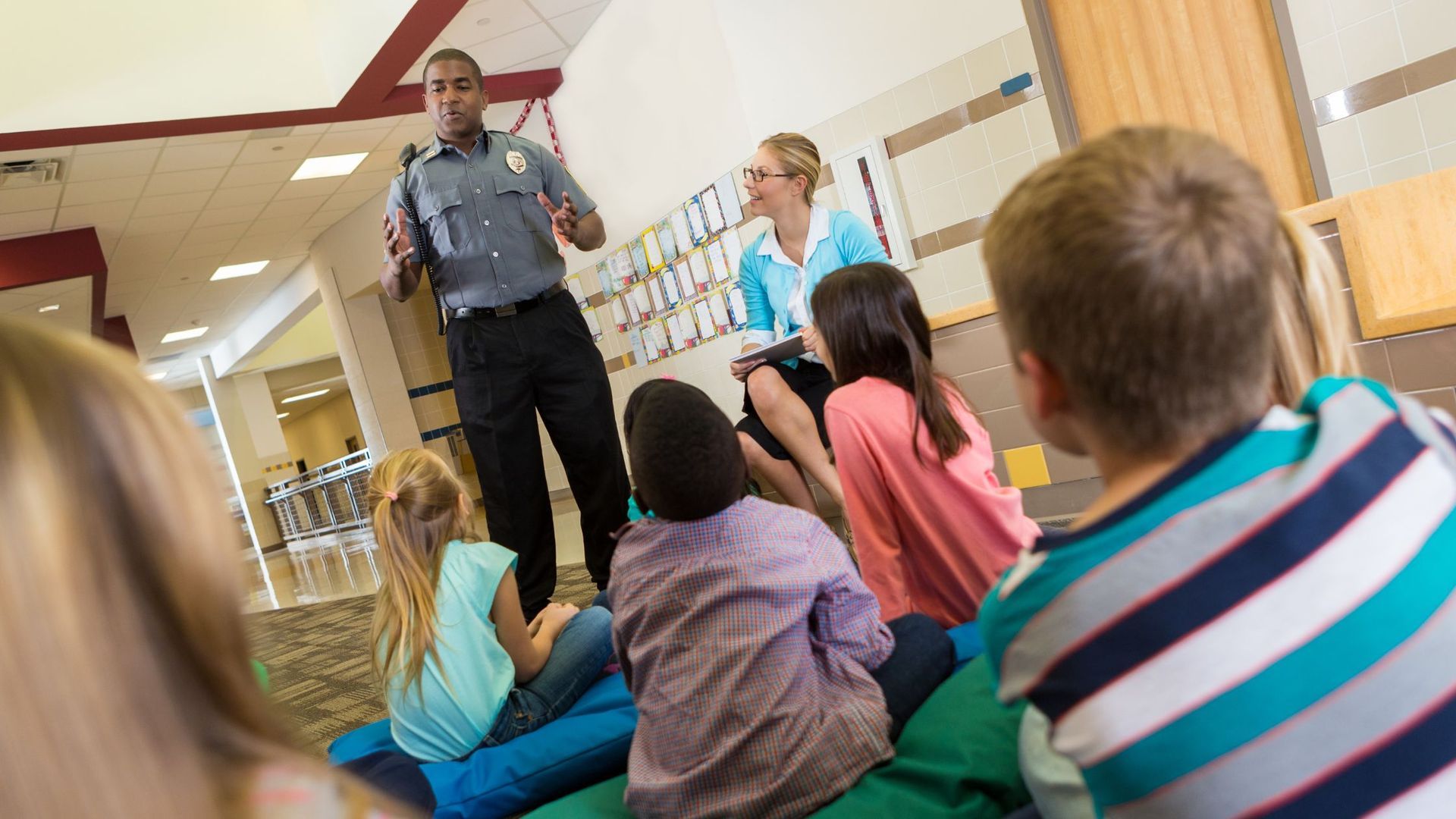 A police officer is giving a presentation to a group of children.
