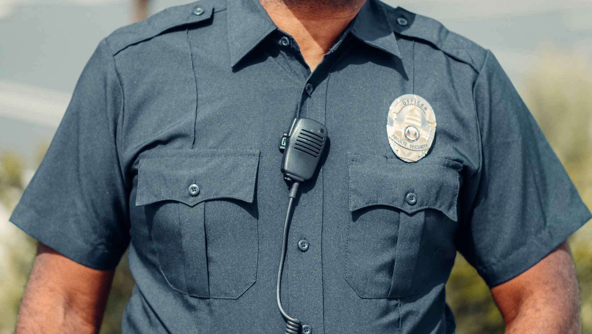 A police officer wearing a blue shirt and a microphone around his neck.