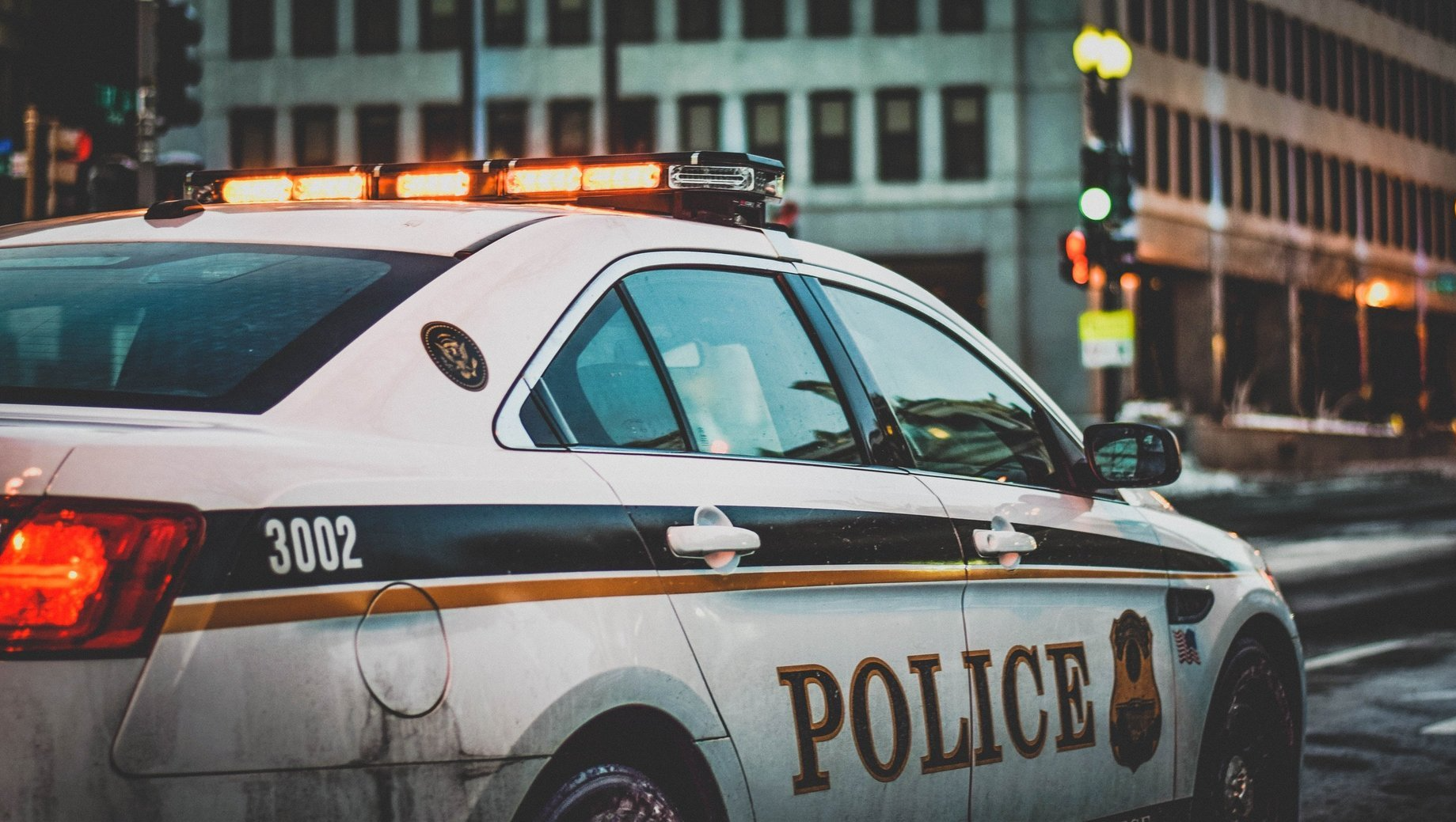 A police car is parked on the side of the road in front of a building.