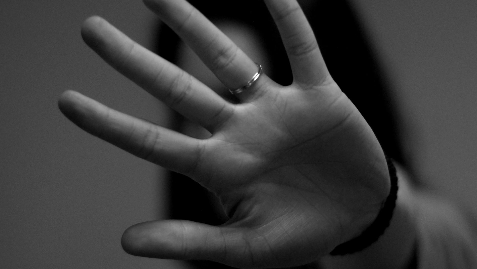 A woman is covering her face with her hand in a black and white photo.