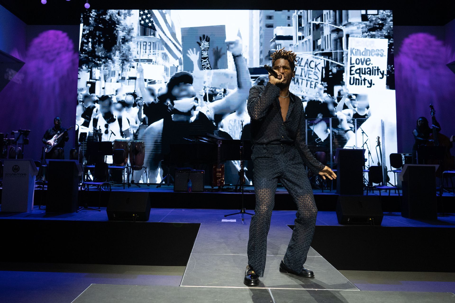 A man is standing on a stage singing into a microphone