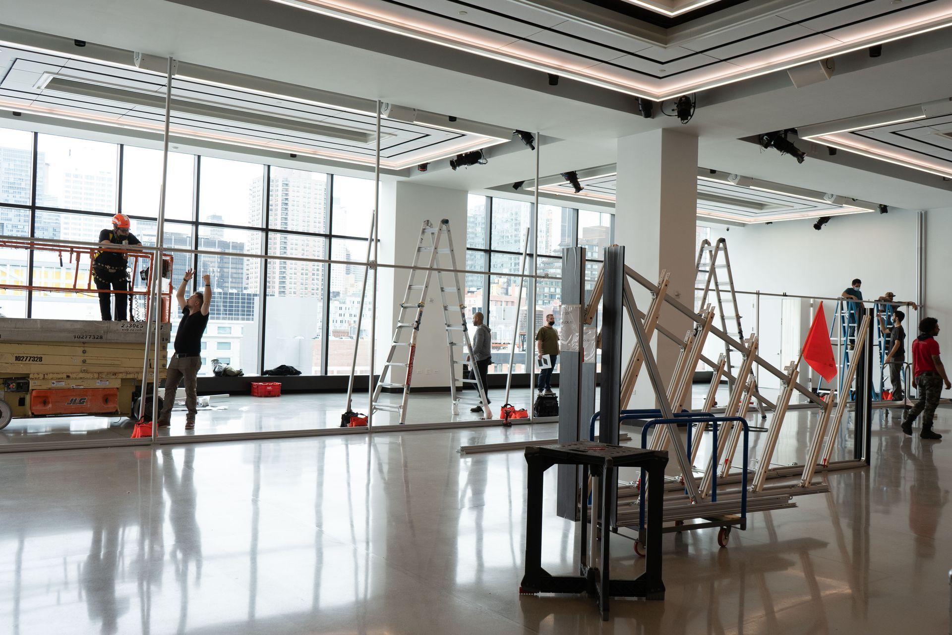 A group of people are working in a large room with a lot of windows.