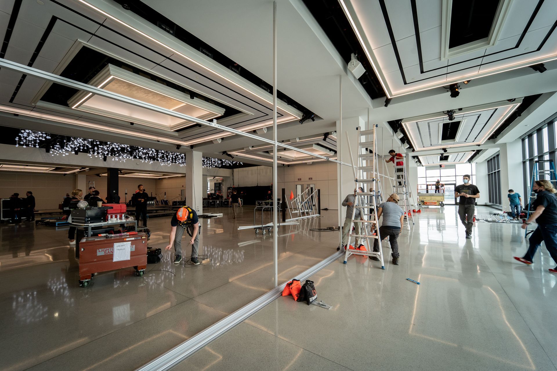 A group of people are working on a large mirror in a large room.