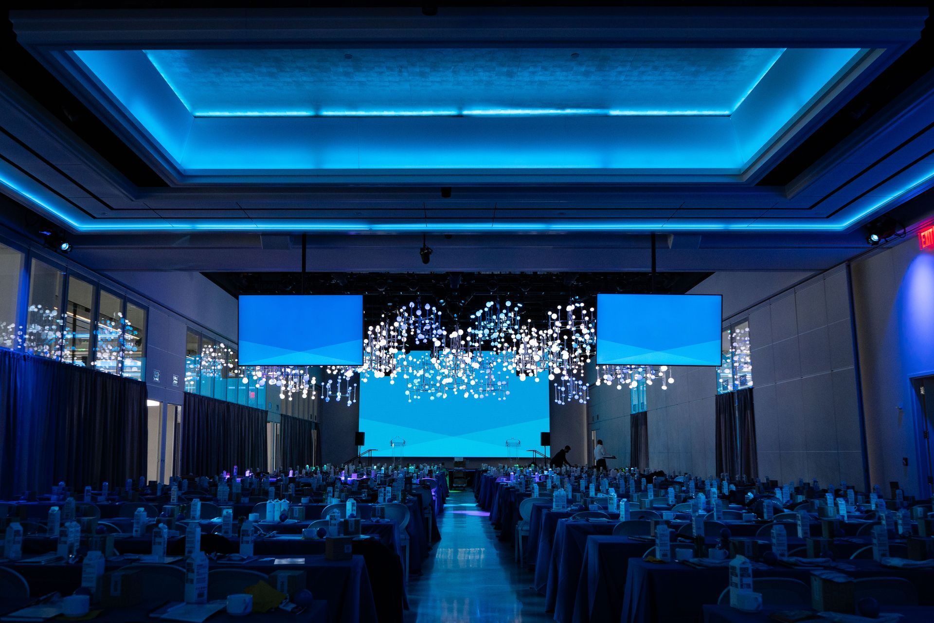 A large room with tables and a large screen on the ceiling