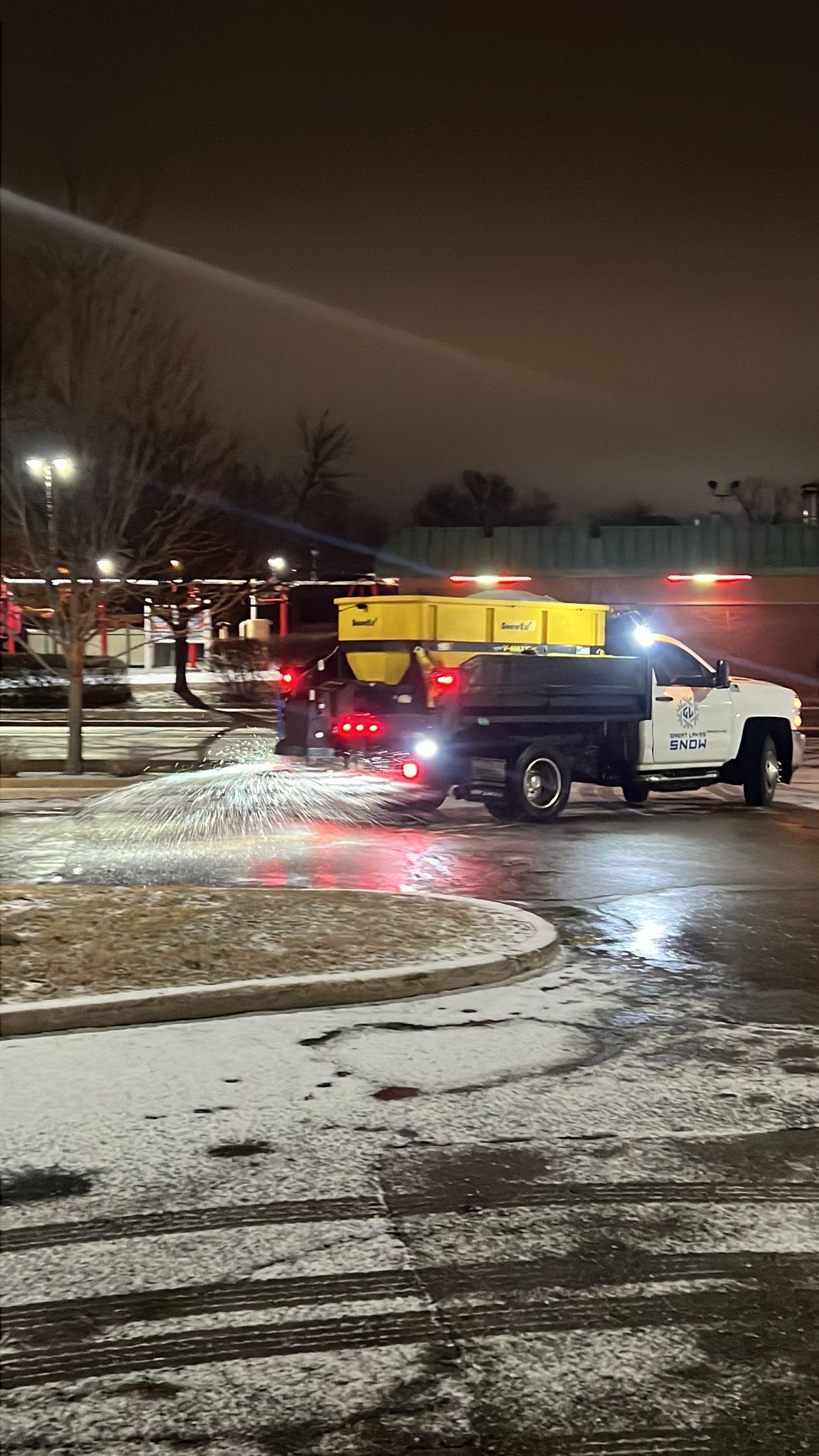 Great Lakes Snow trucks spreading salt across a commercial parking lot.