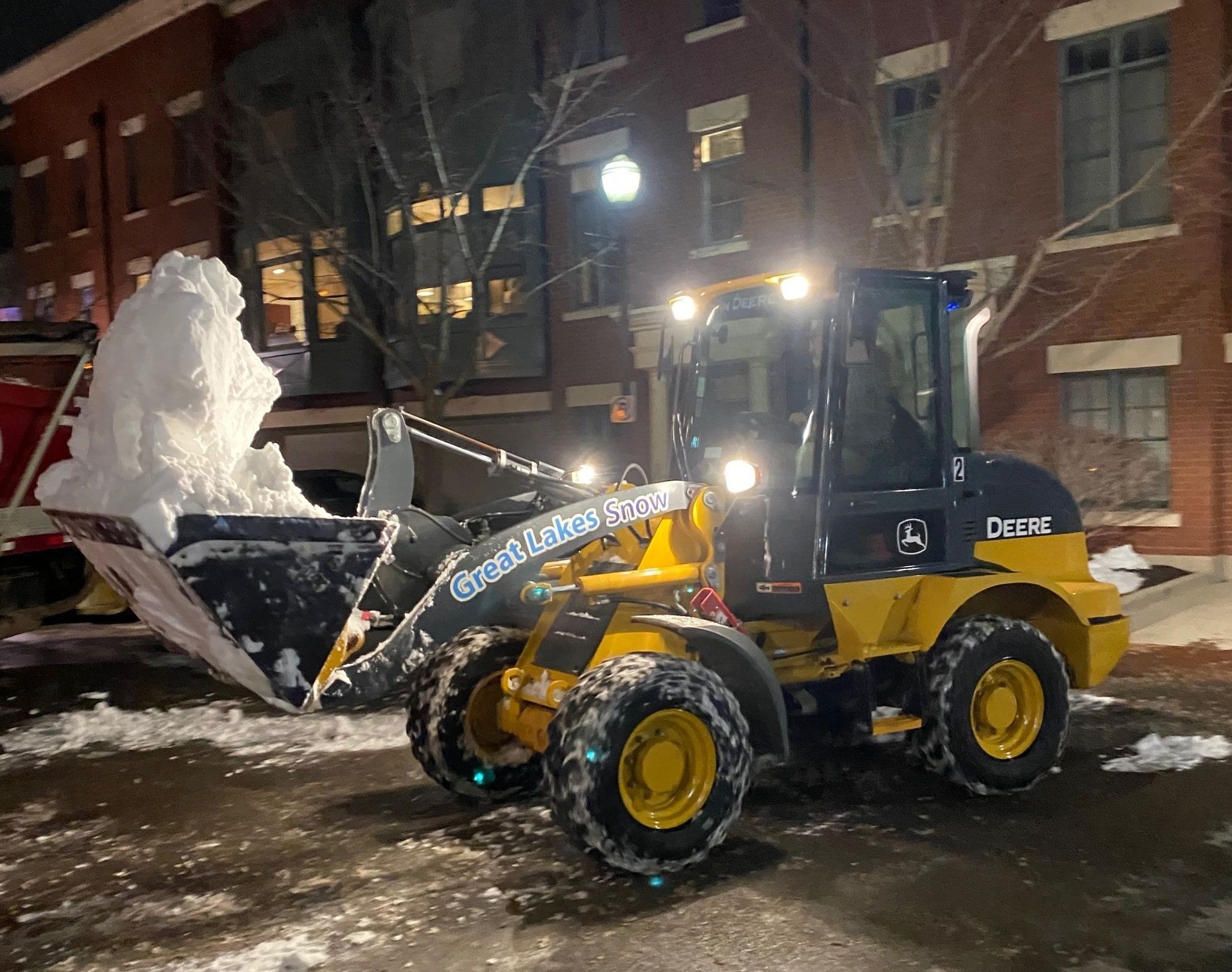 Great Lakes Snow loader removing snow at night on a commercial property for safe winter access.