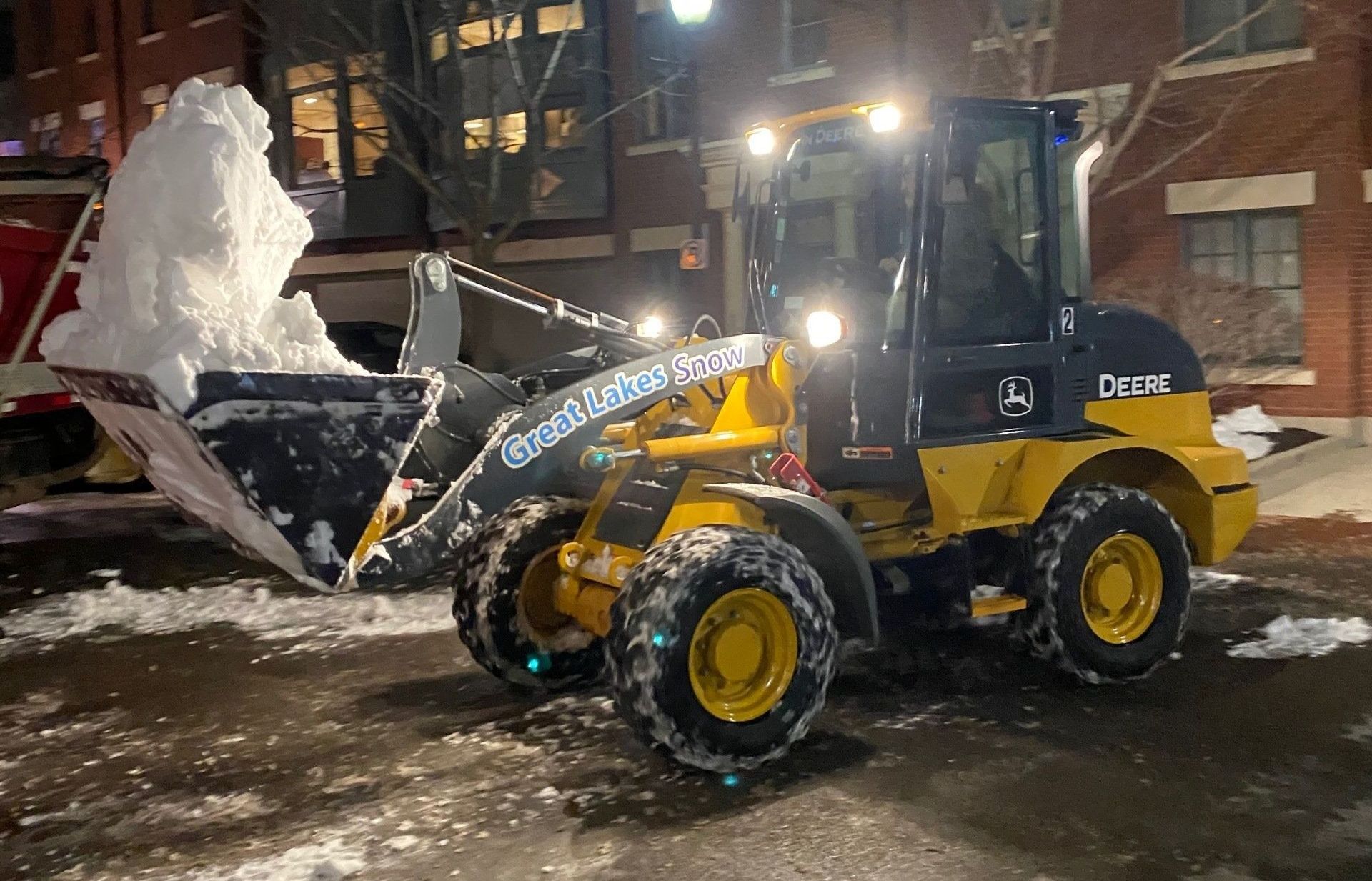 Great Lakes Snow loader removing snow at night on a commercial property for safe winter access.