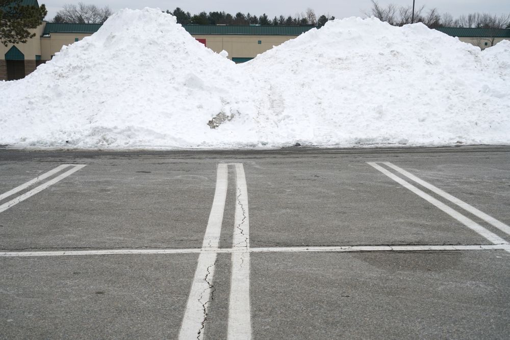 Snowbanks piled behind an empty parking lot with painted white lines
