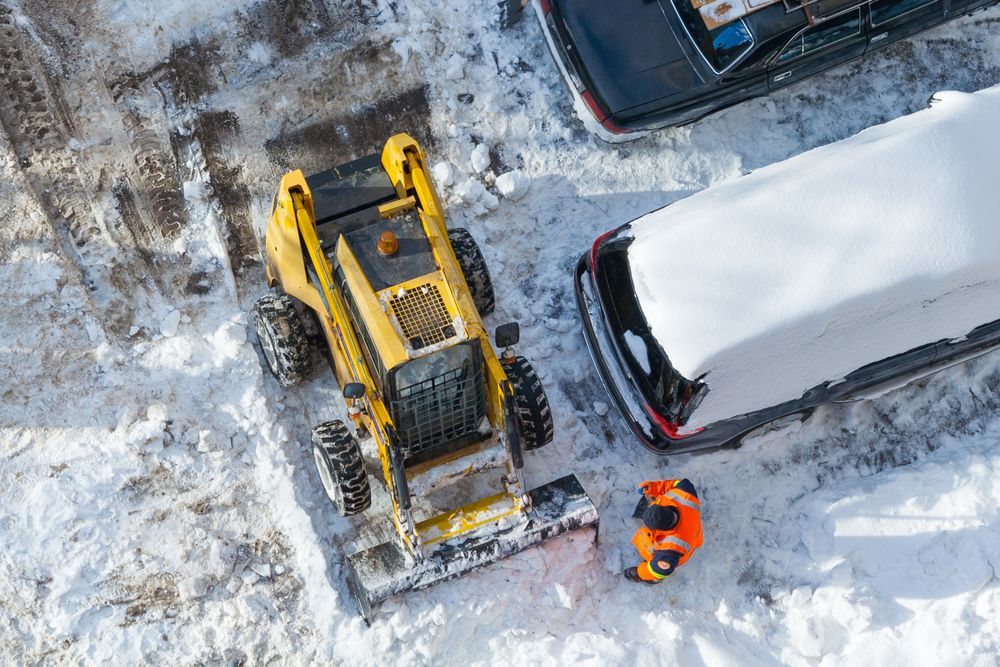 An aerial view of a snow blower clearing a parking lot.