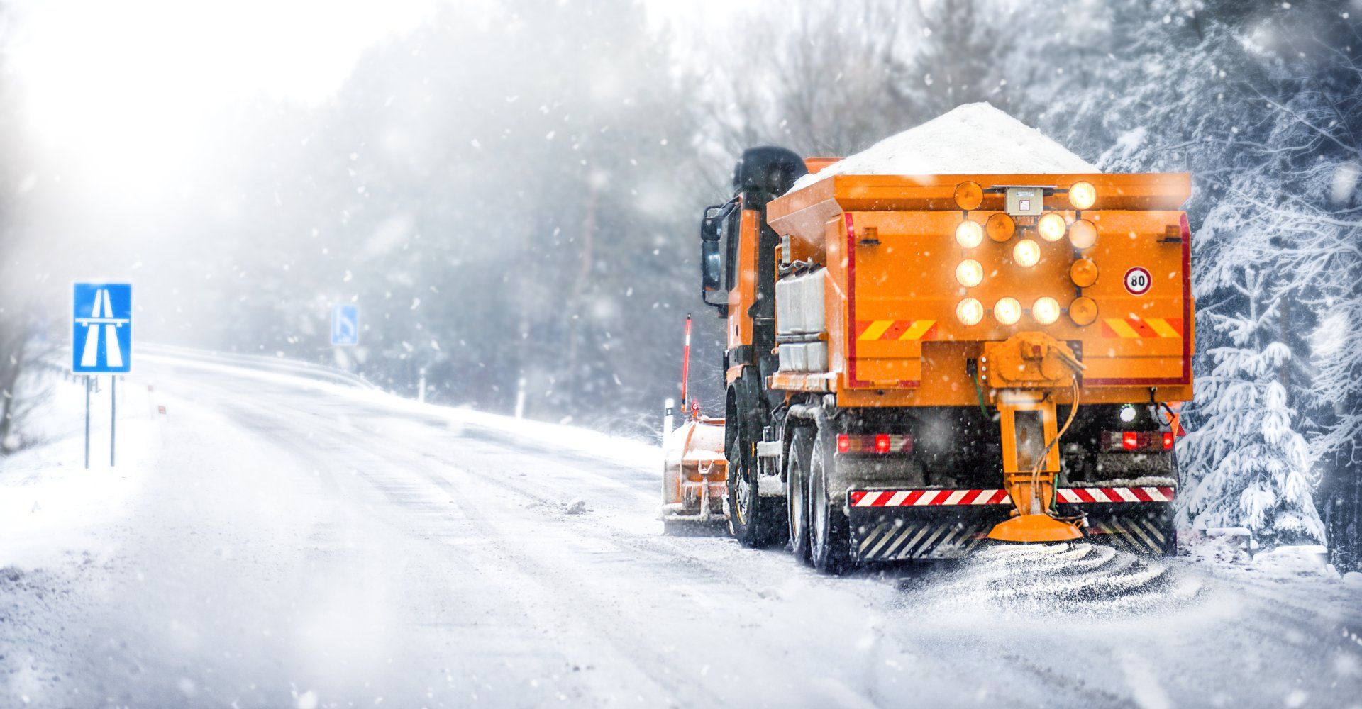 a snowplow clearing the road of snow while dispensing salt