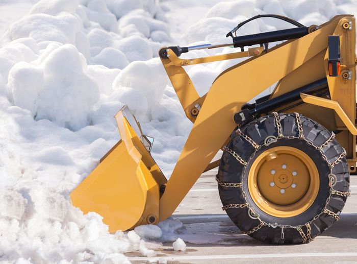 Close-up of front-end loader bucket moving snow for commercial snow removal operations