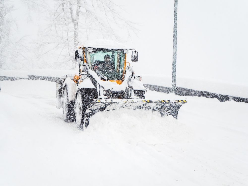 Snowplow clearing snow from a road during a snowstorm.
