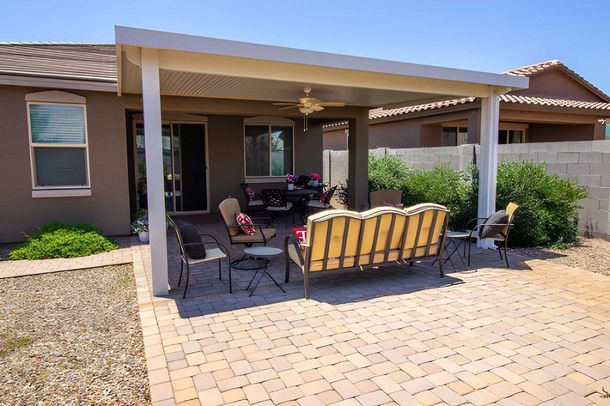 Covered patio with outdoor seating and yellow sofa in a desert-style backyard