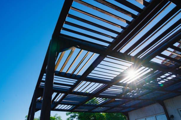 Sunlight shining through a modern pergola against a blue sky