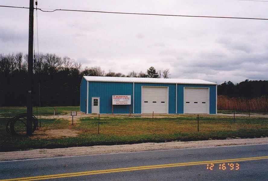 Small blue utility building with two garage doors beside a road on a cloudy day