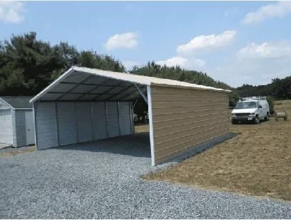 Open-sided metal carport with tan siding beside a white van on gravel and grass.