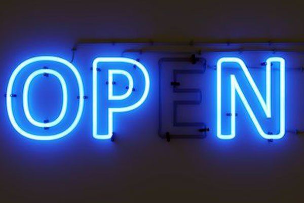 A neon sign that says `` open '' is hanging on a wall.