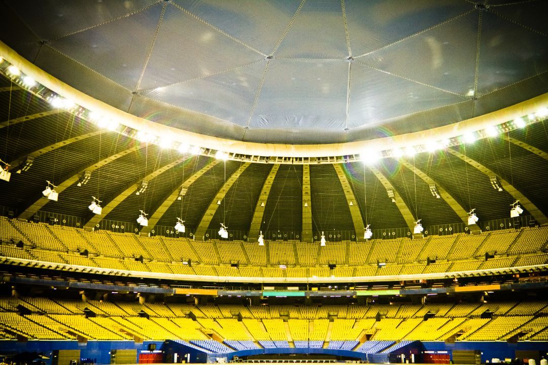 The inside of a stadium with yellow seats and a dome.