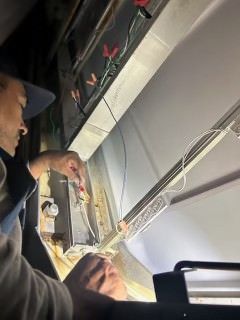 A man is working on a light fixture with a screwdriver.