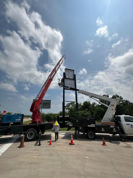 A crane is lifting a large sign in a parking lot.