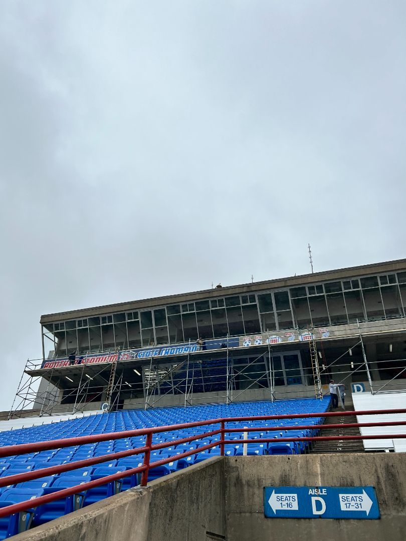 A stadium with blue seats and a red railing and a sign that says stadium d on it.
