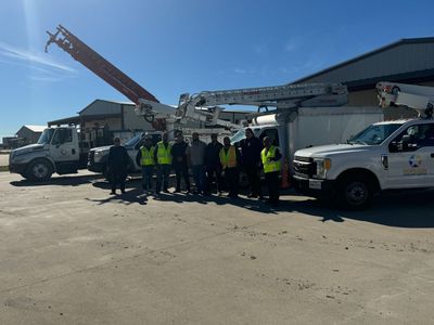 A group of people are standing in front of a row of trucks.