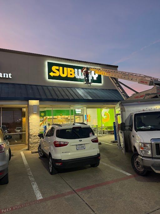A subway sign is being installed on the side of a building