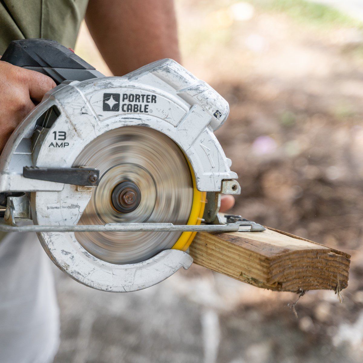 A man is using a porter cable circular saw to cut a piece of wood