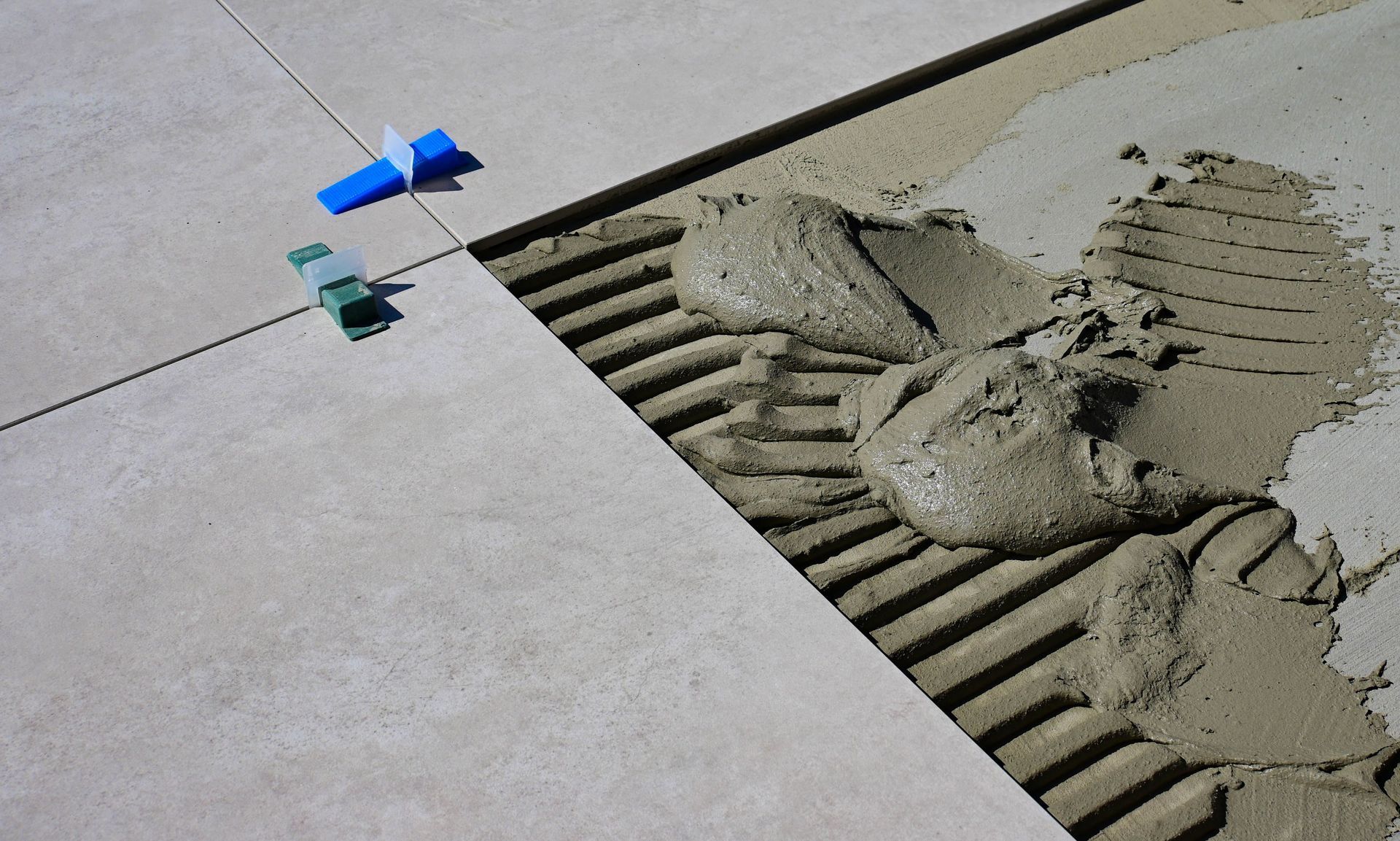 Bathroom renovation with a person drilling near a bathtub and tile floor