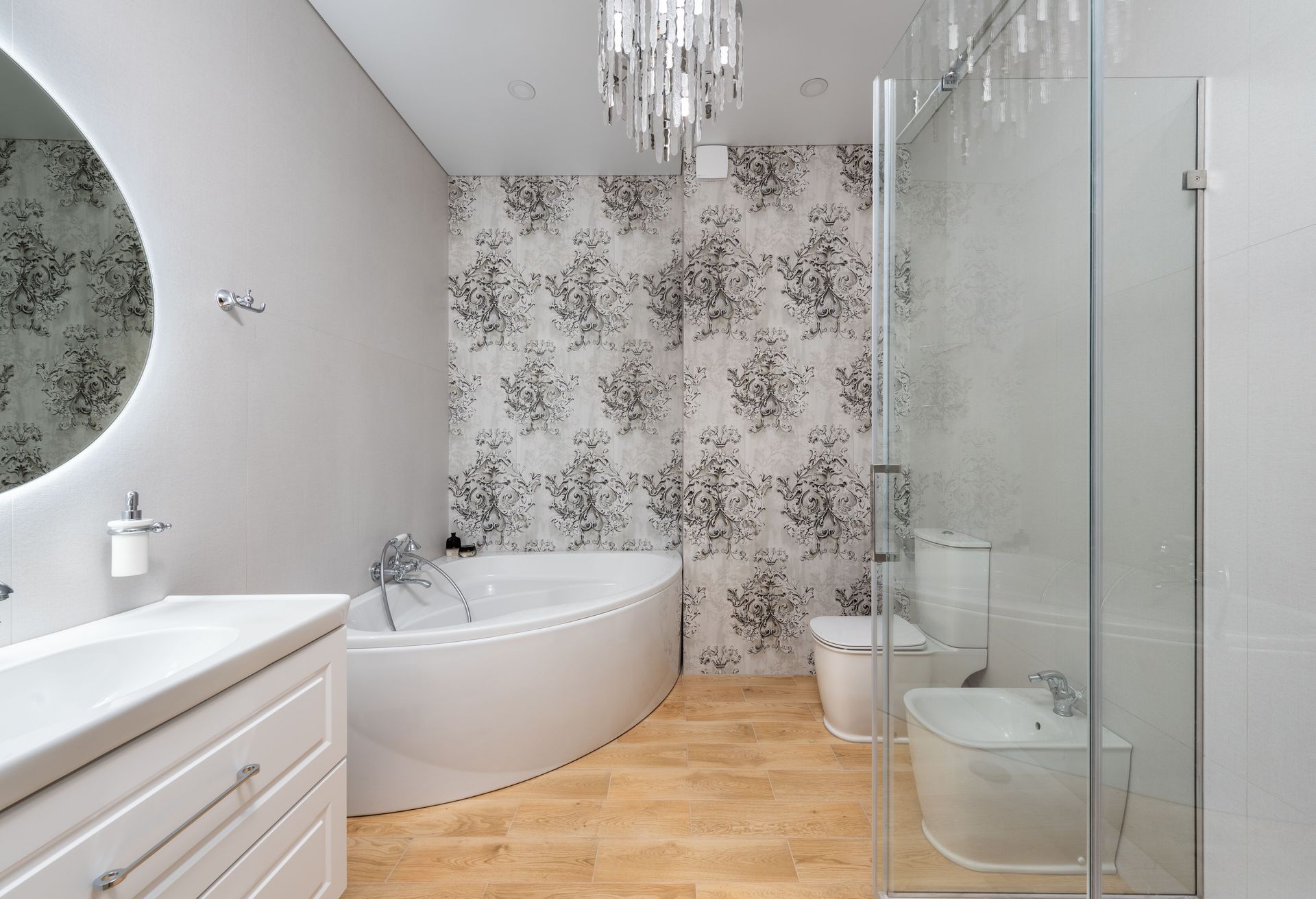 Plumber tightening a bathroom vanity beside a tub and sink