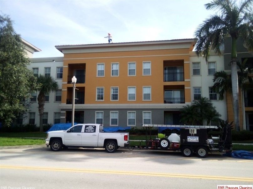 RNR Pressure Cleaning is parked in front of an apartment building that is getting washed.