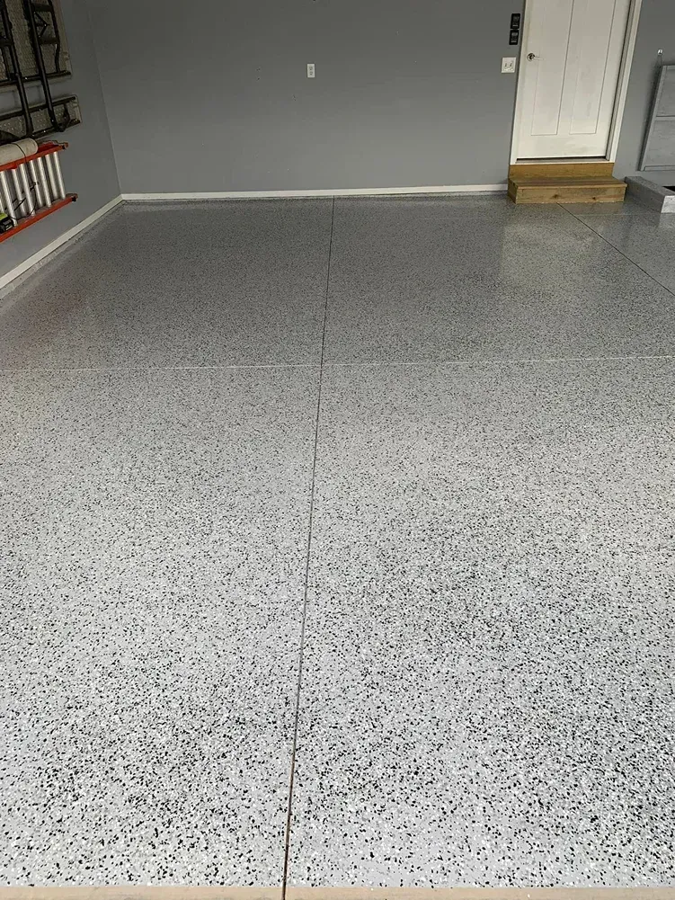 Empty gray speckled garage floor with a crack, in front of a closed door
