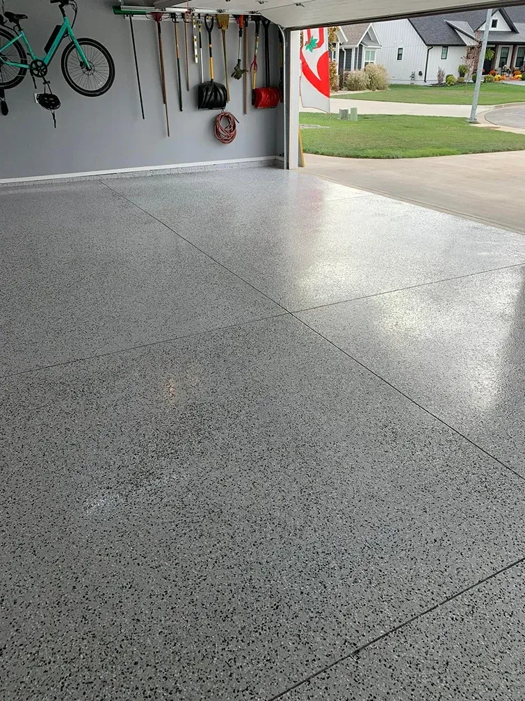 Speckled gray garage floor with open door to a suburban street outside
