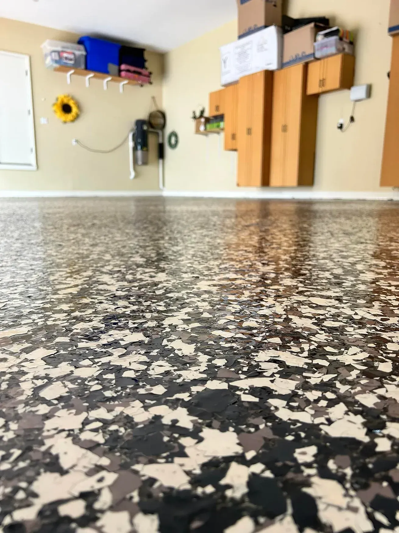 Low-angle view of a garage with black-and-white speckled floor and wall-mounted storage cabinets and tools.