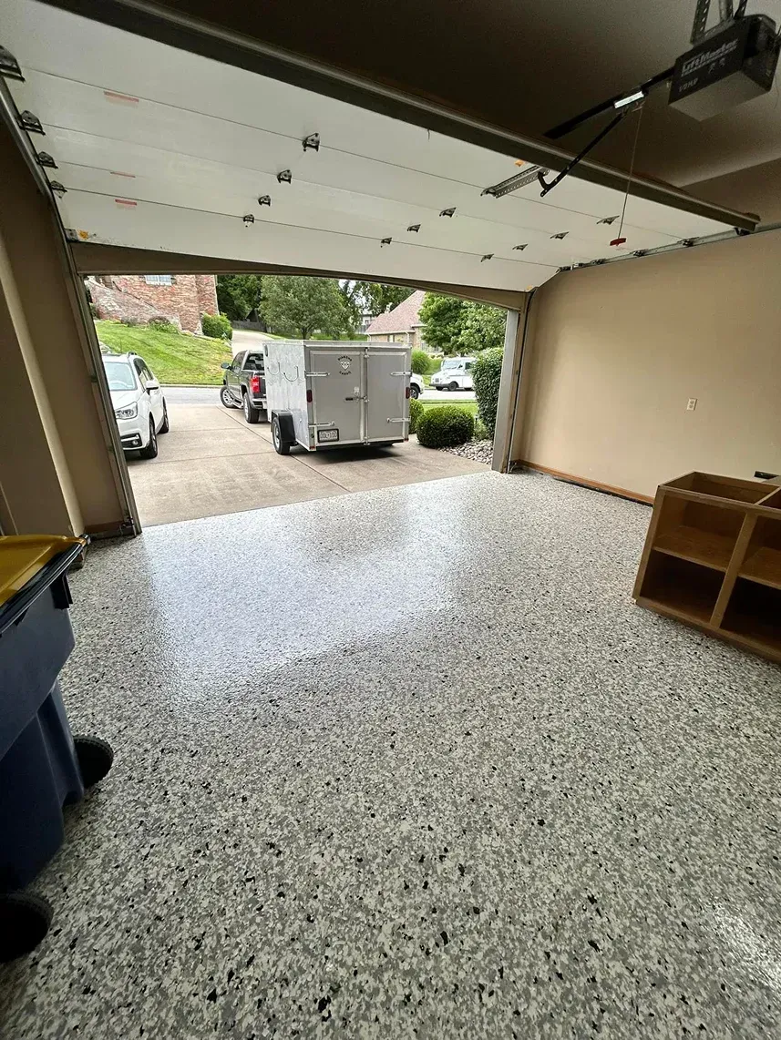 Open garage with speckled floor, white box truck outside, and shelves along the right wall.